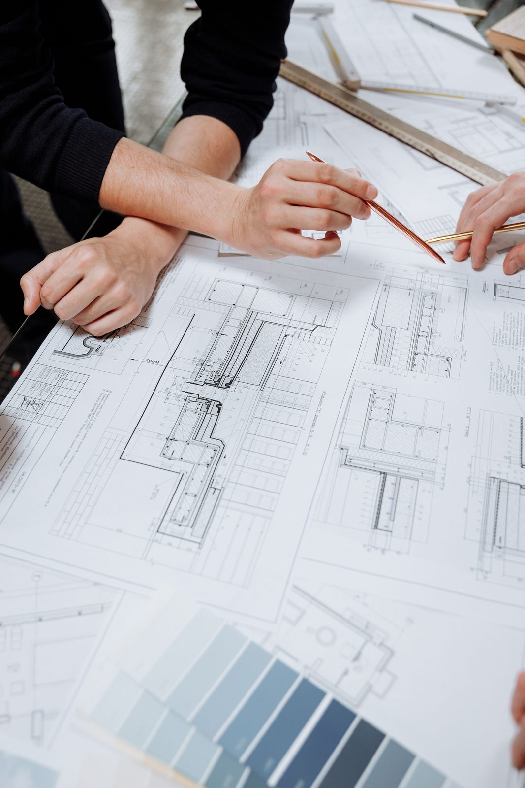 Hands and pencils over a set of architectural drawings on a table